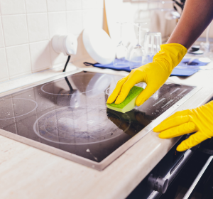 A worker cleaning a stove top in an apartment