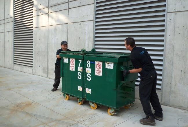 Workers moving garbage bins